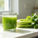 Fresh organic celery juice protocol in a glass mug on a white quartz kitchen table for chronic gastritis cure and liver detox.